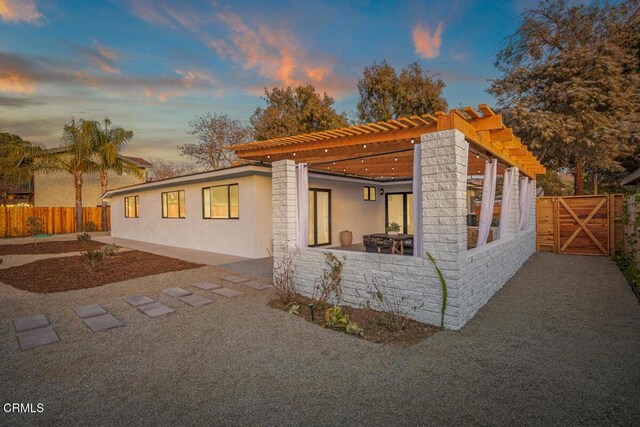 view of home's exterior with a patio, fence, a gate, a pergola, and stucco siding