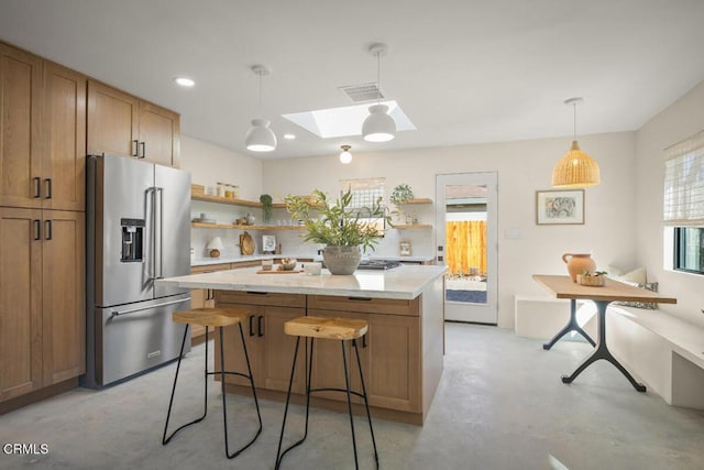 kitchen with a skylight, visible vents, a kitchen island, high quality fridge, and open shelves