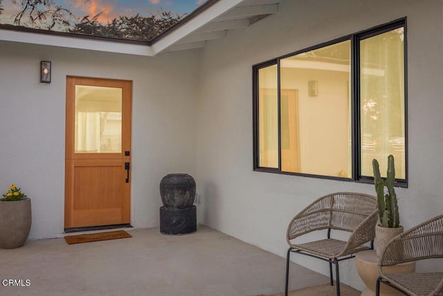 exterior entry at dusk with a patio and stucco siding