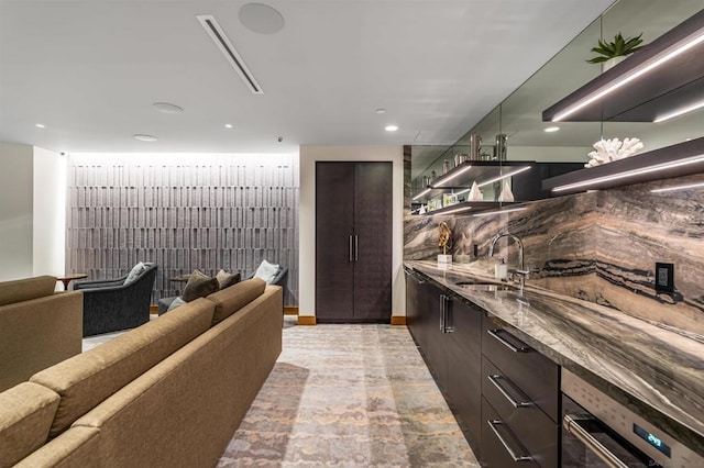 kitchen featuring dark brown cabinetry, sink, oven, and dark stone counters