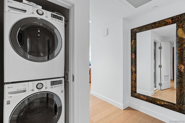 laundry room with stacked washer / drying machine and light wood-type flooring