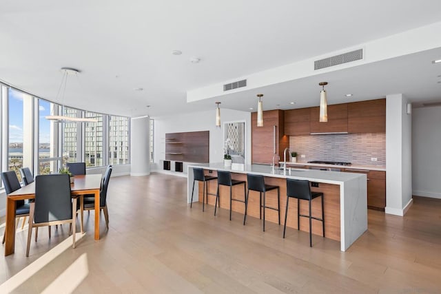 kitchen featuring a large island, sink, tasteful backsplash, decorative light fixtures, and stainless steel gas stovetop