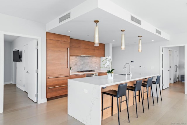 kitchen with pendant lighting, sink, a breakfast bar area, backsplash, and a spacious island