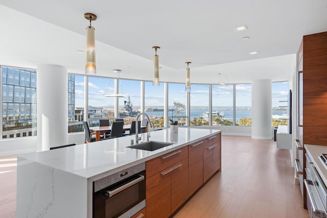 kitchen featuring pendant lighting, sink, stainless steel appliances, a water view, and a center island with sink