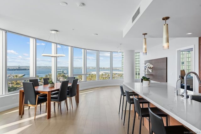 dining area with a water view, sink, and light hardwood / wood-style flooring