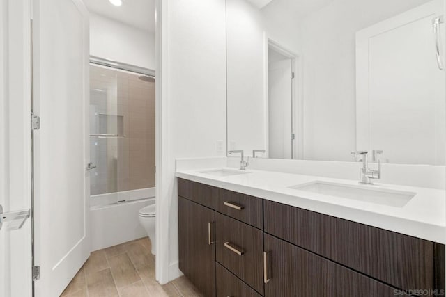 full bathroom featuring toilet, enclosed tub / shower combo, and vanity