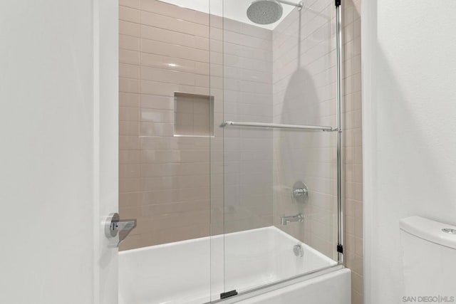 bathroom with toilet and bath / shower combo with glass door