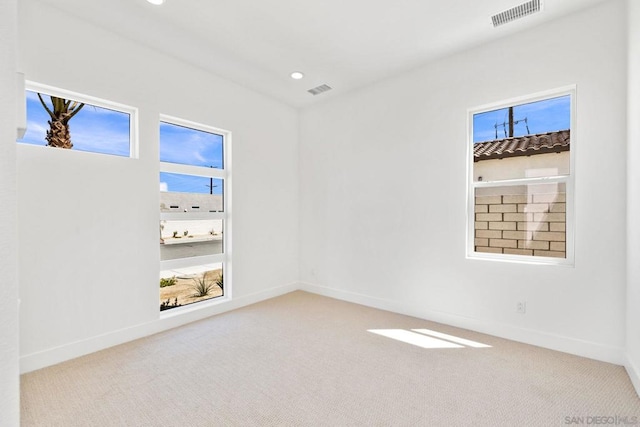 unfurnished room with light colored carpet and plenty of natural light