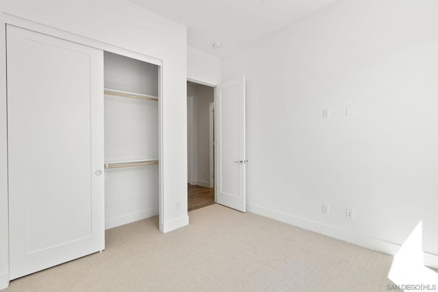 unfurnished bedroom with a closet and light carpet