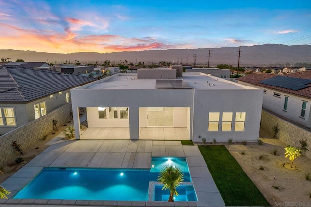 back house at dusk featuring a fenced in pool and a mountain view