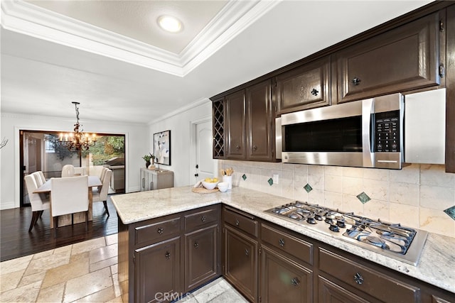 kitchen with dark brown cabinetry, an inviting chandelier, stainless steel appliances, and pendant lighting