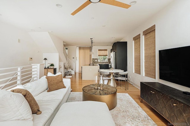 living room with light wood-type flooring and ceiling fan