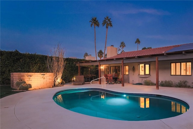 pool at dusk featuring a patio