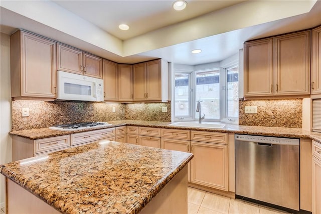 kitchen with light tile patterned floors, stainless steel appliances, sink, light stone countertops, and a center island