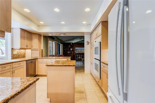 kitchen featuring decorative backsplash, light brown cabinets, white appliances, light stone countertops, and sink