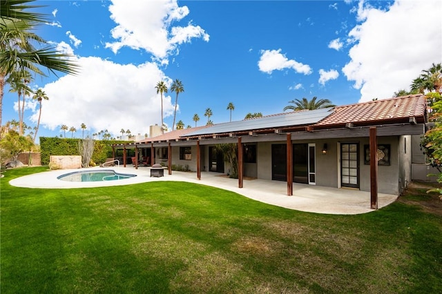 back of house with a yard, a patio area, solar panels, and a fenced in pool