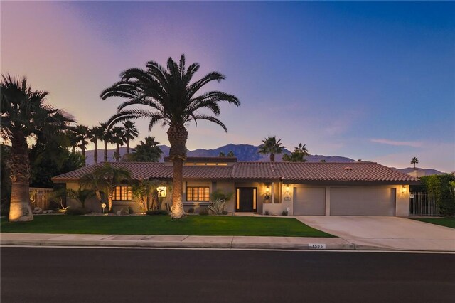 view of front facade with a lawn, a mountain view, and a garage