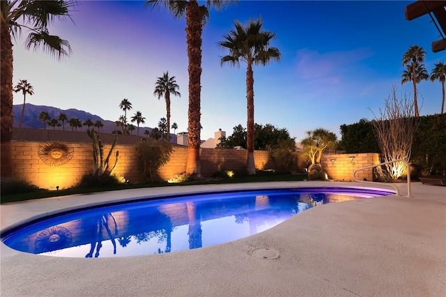 pool at dusk featuring a mountain view