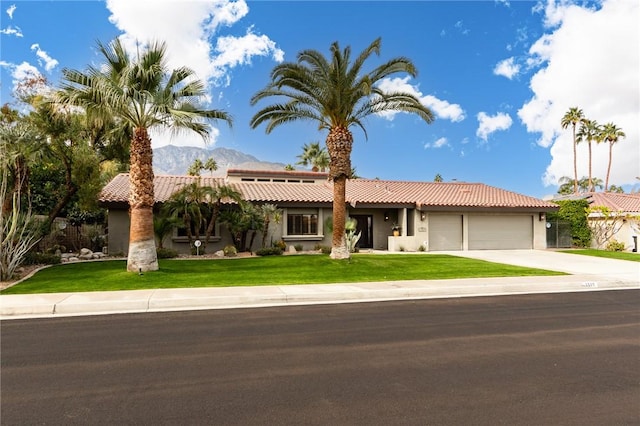 view of front of house with a garage, a front lawn, and a mountain view