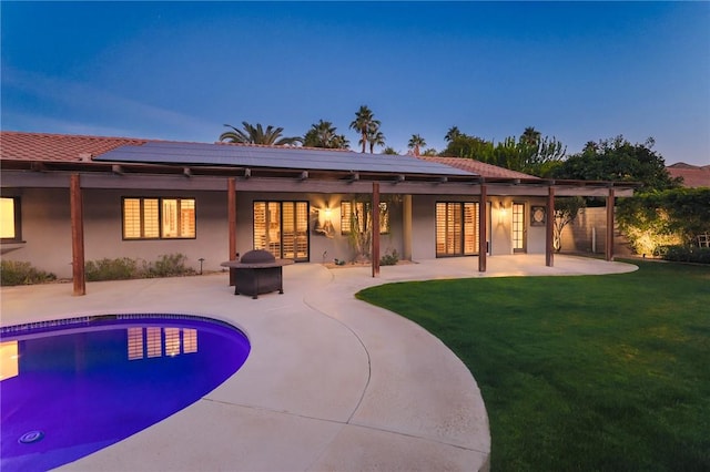 back house at dusk with a yard, a patio area, and a fire pit