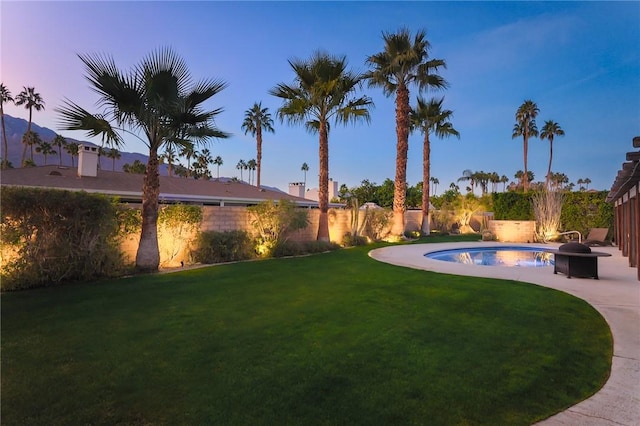 yard at dusk with a patio area, an outdoor fire pit, and a fenced in pool