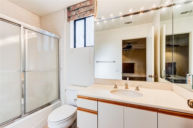 full bathroom with toilet, ceiling fan, vanity, and bath / shower combo with glass door