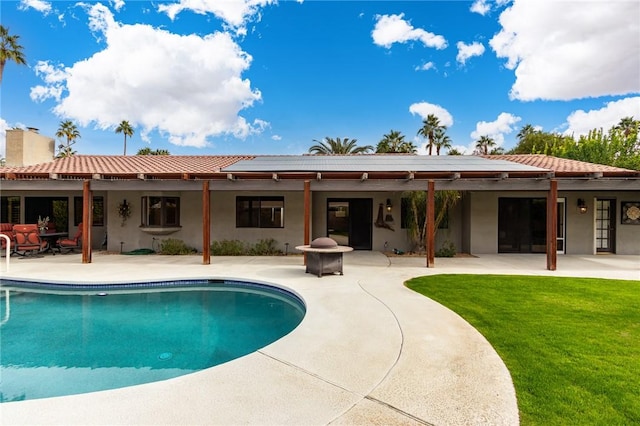 rear view of property with a yard, solar panels, and a patio