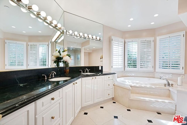 bathroom featuring tiled tub, vanity, and tile patterned flooring