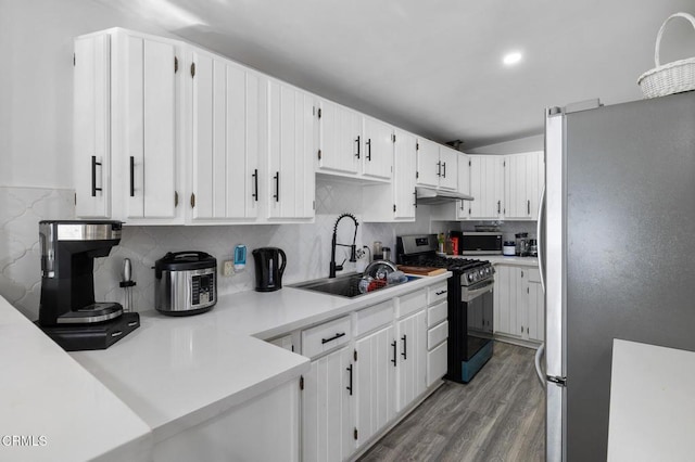 kitchen featuring hardwood / wood-style flooring, stainless steel appliances, tasteful backsplash, white cabinets, and sink