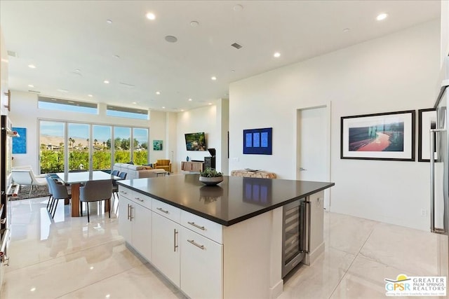 kitchen featuring beverage cooler, white cabinets, and a center island