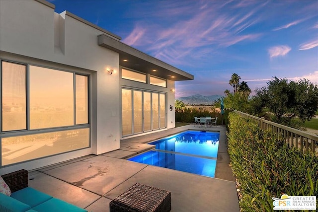 pool at dusk featuring a patio area and a mountain view