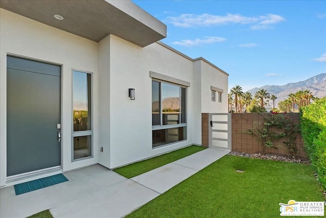 doorway to property with a mountain view and a yard