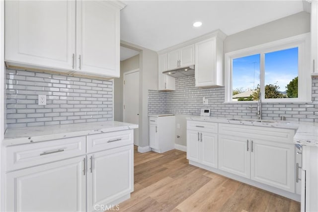 kitchen featuring tasteful backsplash, white cabinets, sink, and light hardwood / wood-style floors