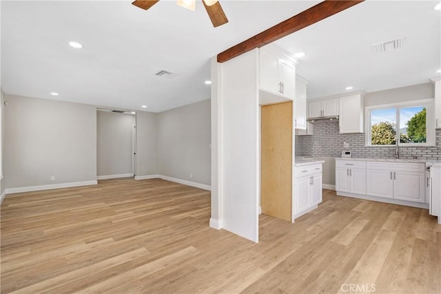 kitchen with white cabinetry, ceiling fan, tasteful backsplash, light hardwood / wood-style flooring, and sink