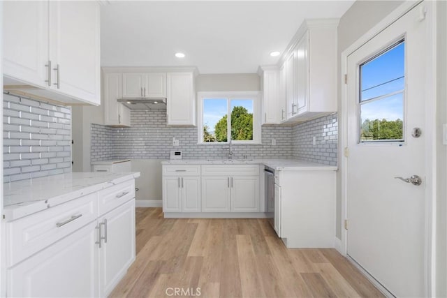 kitchen with light stone counters, sink, white cabinetry, and backsplash