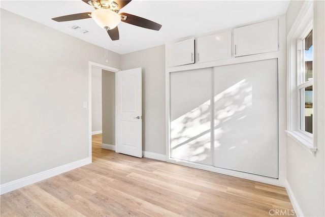 unfurnished bedroom with light wood-type flooring, ceiling fan, and a closet