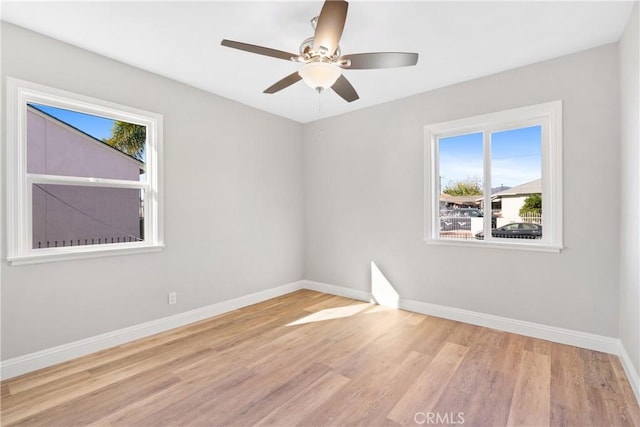 unfurnished room featuring ceiling fan, a wealth of natural light, and light wood-type flooring