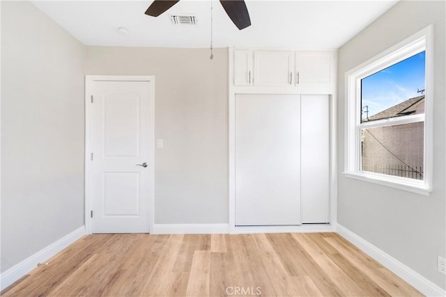 unfurnished bedroom featuring ceiling fan, light wood-type flooring, and a closet