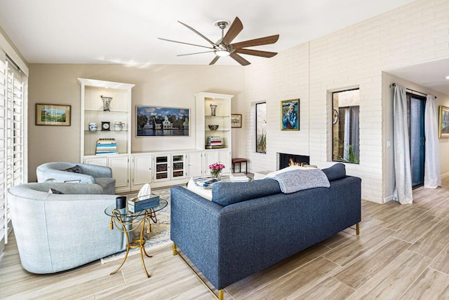 living room featuring ceiling fan, vaulted ceiling, and a fireplace