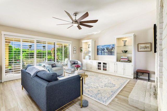 living room featuring ceiling fan, vaulted ceiling, a fireplace, and light hardwood / wood-style flooring