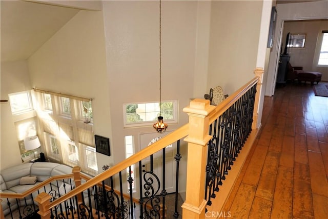 stairway with hardwood / wood-style floors, high vaulted ceiling, and a chandelier