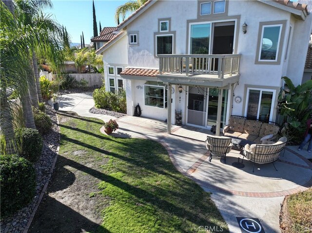 rear view of house with a yard, a patio area, outdoor lounge area, and a balcony