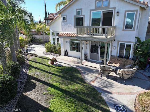 rear view of property featuring a balcony, a patio, and a lawn