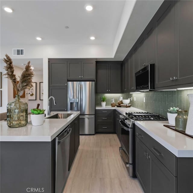 kitchen with light tile patterned flooring, appliances with stainless steel finishes, backsplash, and sink