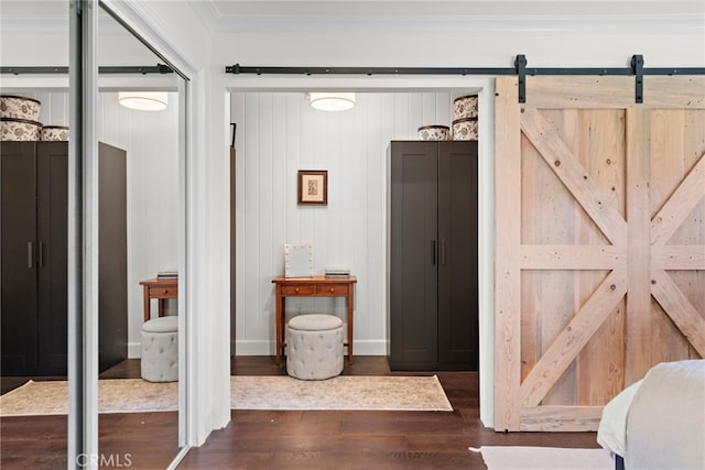 interior space with dark wood-type flooring, ornamental molding, a barn door, and wooden walls