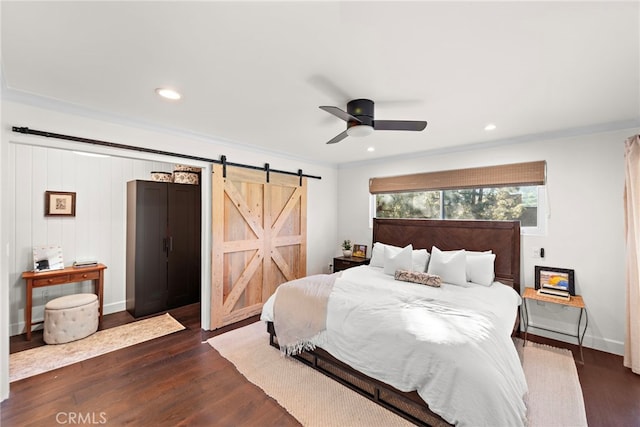 bedroom featuring ceiling fan, ornamental molding, a barn door, and dark hardwood / wood-style floors