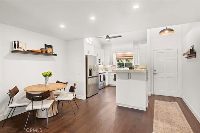 kitchen featuring white cabinetry, kitchen peninsula, stainless steel appliances, decorative light fixtures, and dark wood-type flooring