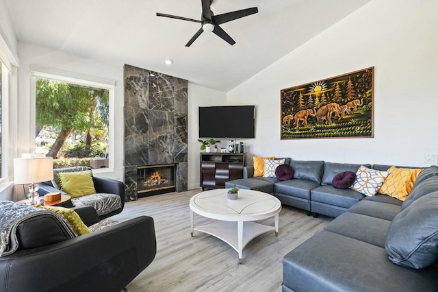 living room with light hardwood / wood-style floors, a high end fireplace, lofted ceiling, and a healthy amount of sunlight