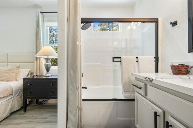 bathroom featuring wood-type flooring, combined bath / shower with glass door, and vanity