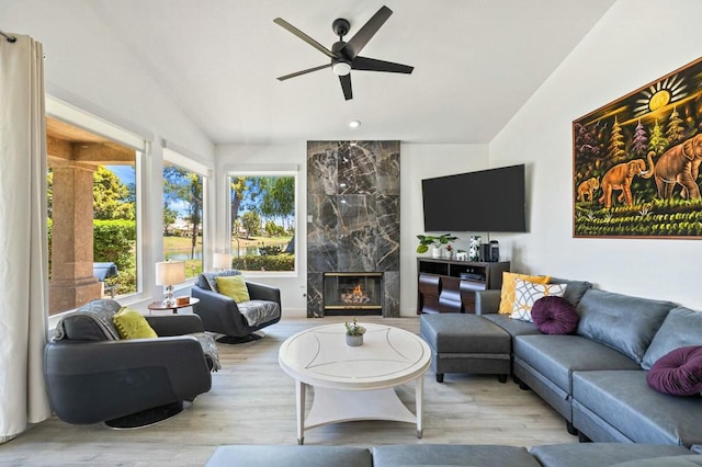 living room featuring lofted ceiling, light wood-type flooring, a fireplace, and ceiling fan